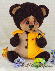 Медвежонок Тишка сидит и кушает конфеты
