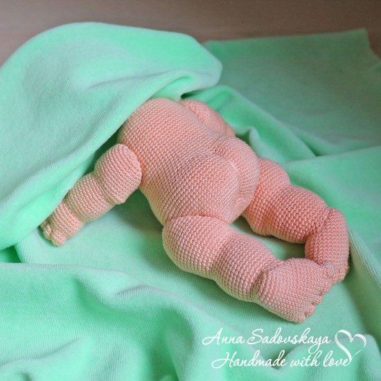 Вязаный пупсик лежит на животике